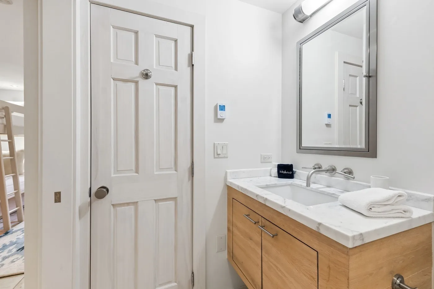 Un lavabo de baño con espejo y una puerta blanca con paneles.