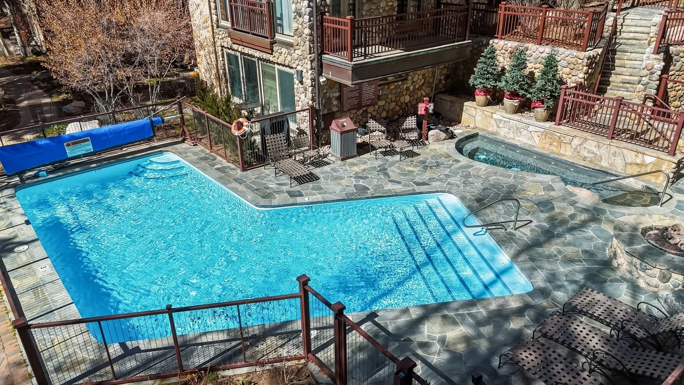Una piscina al aire libre con patio de piedra y barandillas alrededor.