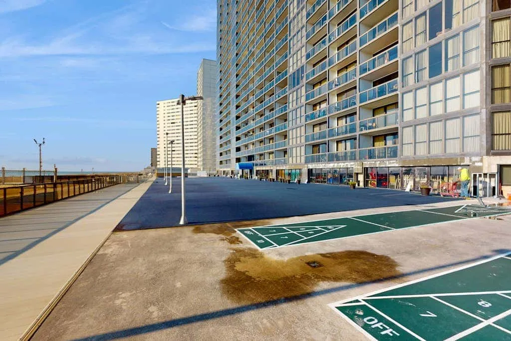 A paved outdoor area beside a tall building has marked sports courts.