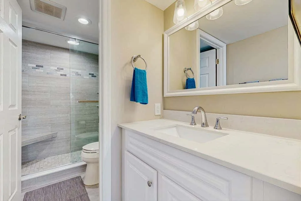 A bright bathroom with a double-sink vanity and glass shower.