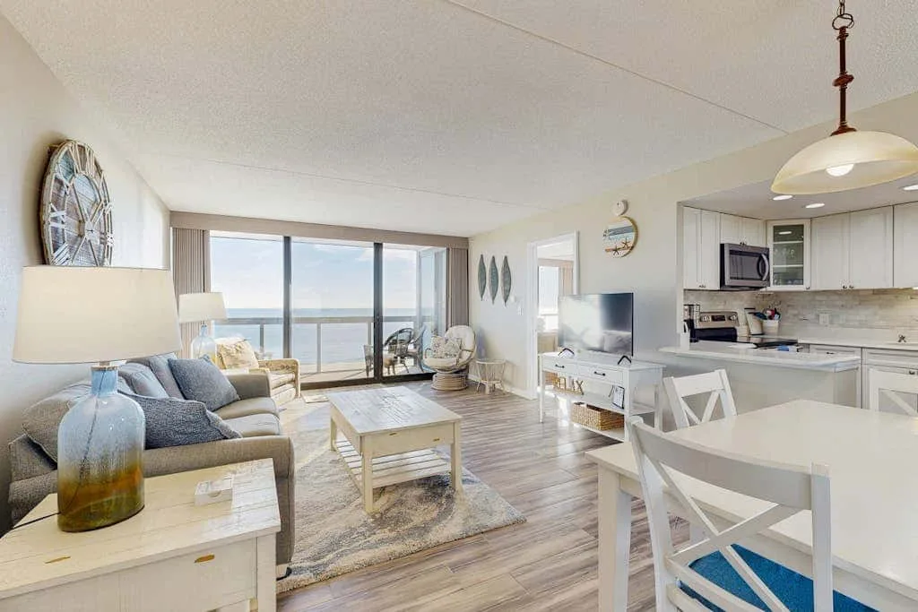 A bright open-plan living and dining area with large windows and a kitchen.
