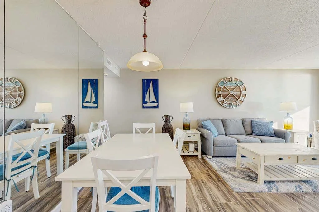 A bright dining and living area with a white table and gray seating.