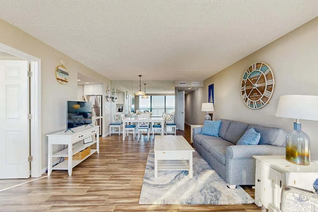 A living room with seating and a dining area beyond.