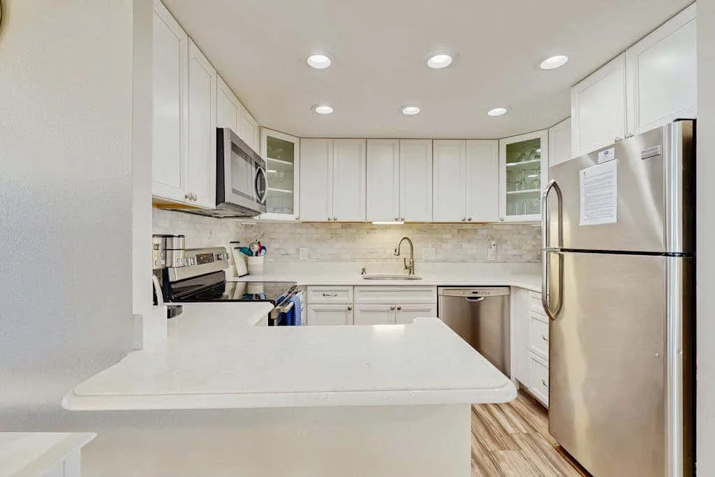 A bright kitchen with white cabinets, a countertop, and stainless steel appliances.