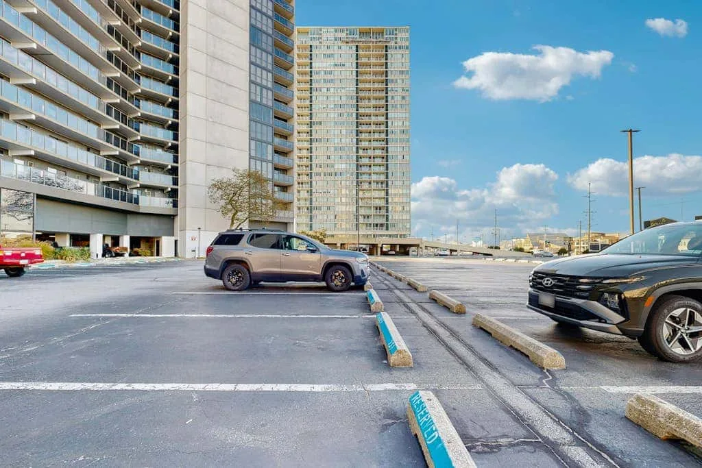 A parking lot with parked cars in front of high-rise buildings.