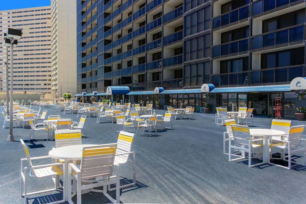 An outdoor seating area with rows of tables and chairs beside a modern building.