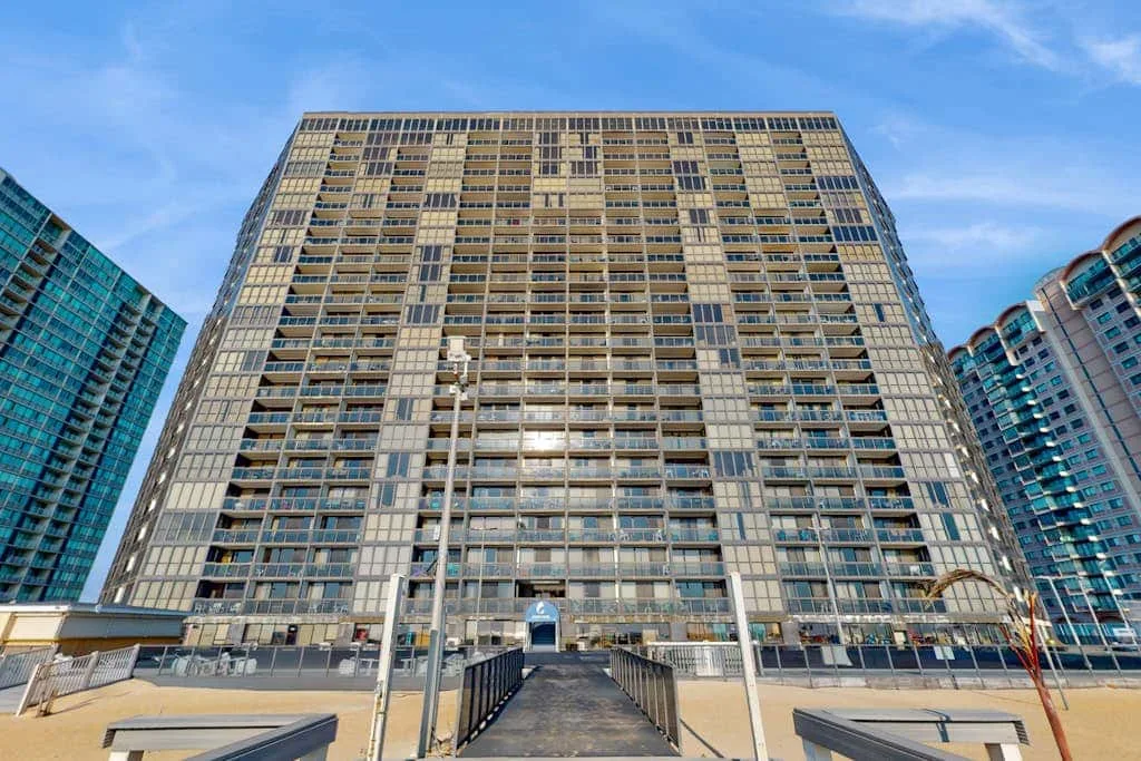 A tall high-rise apartment building stands beneath a blue sky.