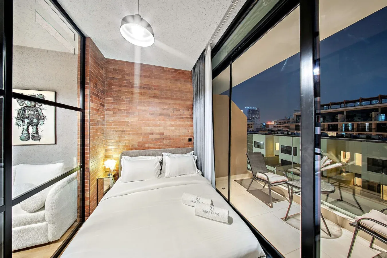 Un dormitorio con una cama bien tendida junto a puertas de vidrio de piso a techo.