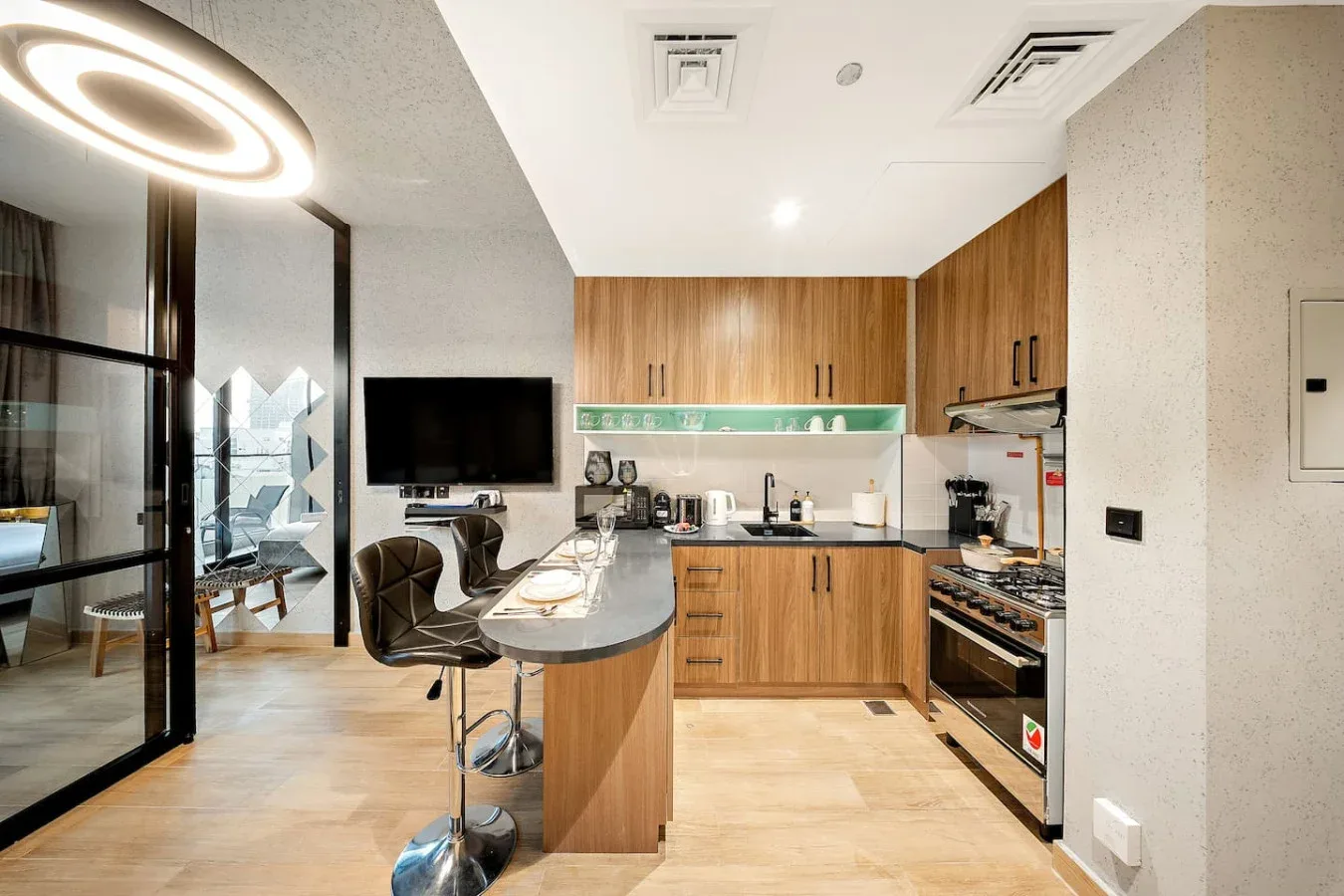 Una cocina moderna con gabinetes de madera y una barra de comedor junto a puertas de vidrio.