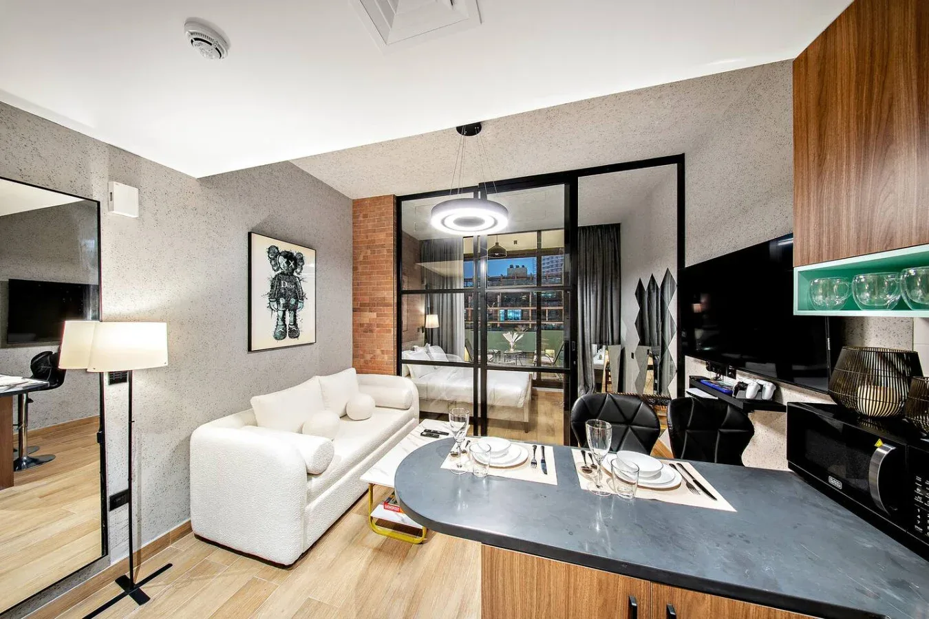 Una sala moderna con asientos blancos junto a una isla de cocina y puertas de vidrio.