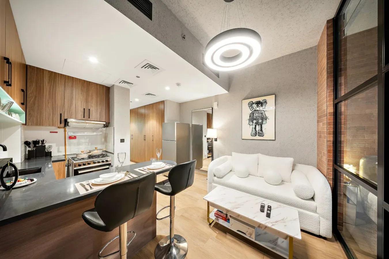 Una cocina y comedor modernos se conectan con una sala de estar con asientos blancos.