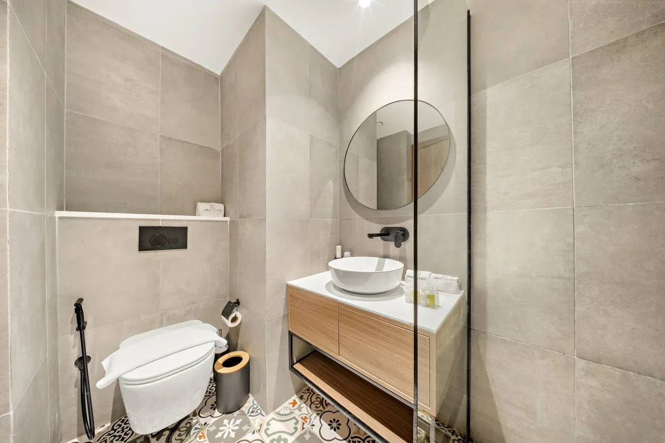 Un baño con azulejos, inodoro, tocador y mampara de vidrio.