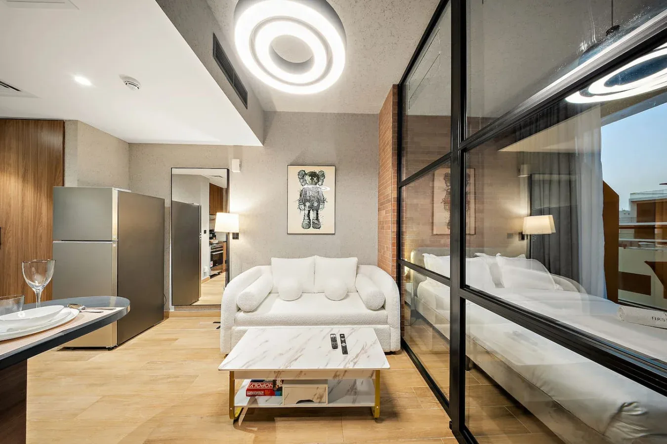 Una sala moderna con asientos blancos, una mesa de centro y una pared de vidrio.