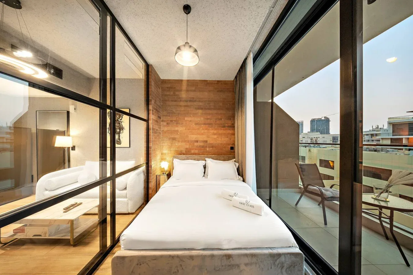 Un dormitorio con una cama blanca entre paredes de vidrio y una pared revestida de madera.