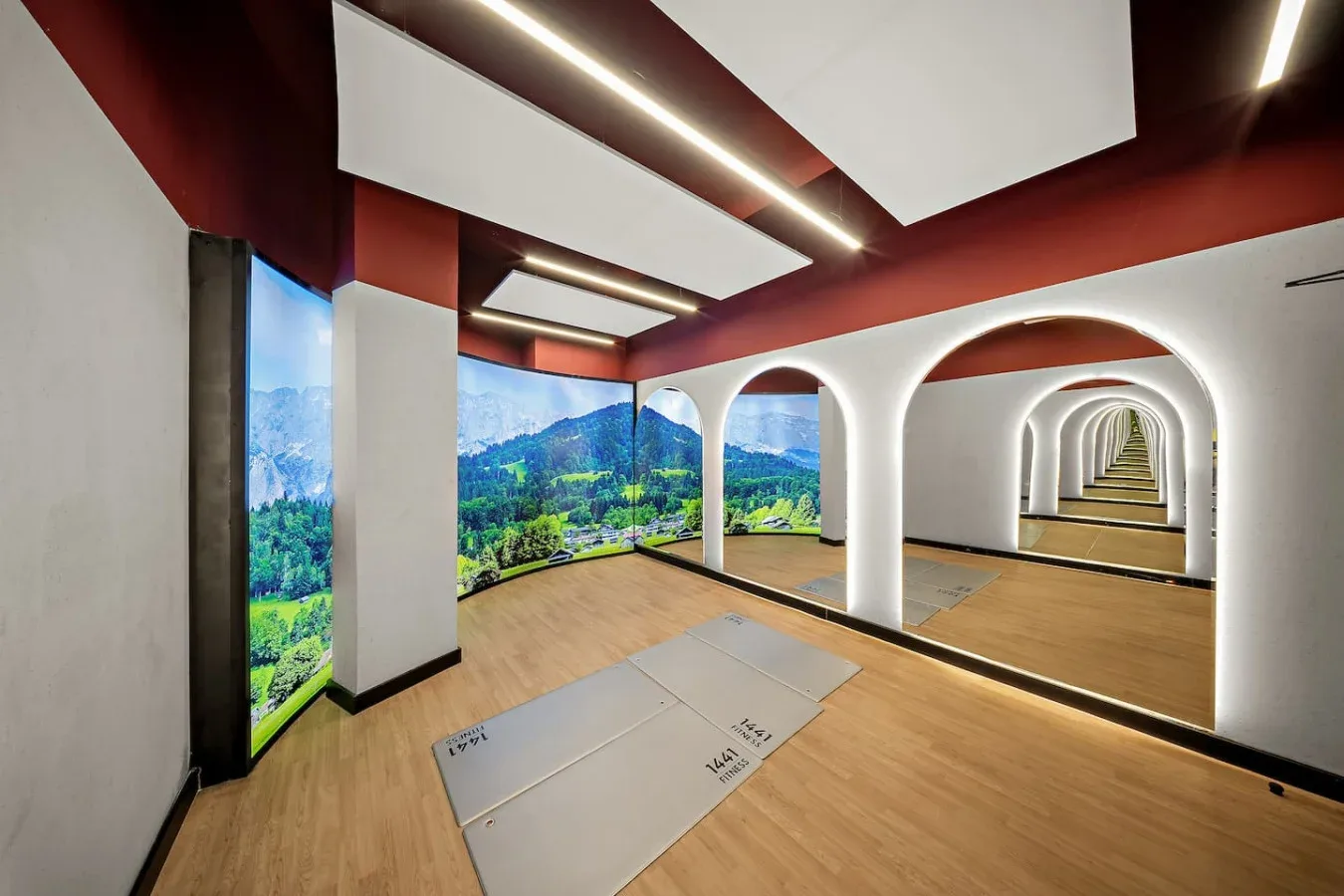 Un luminoso estudio de ejercicio tiene suelo de madera y aberturas arqueadas iluminadas.