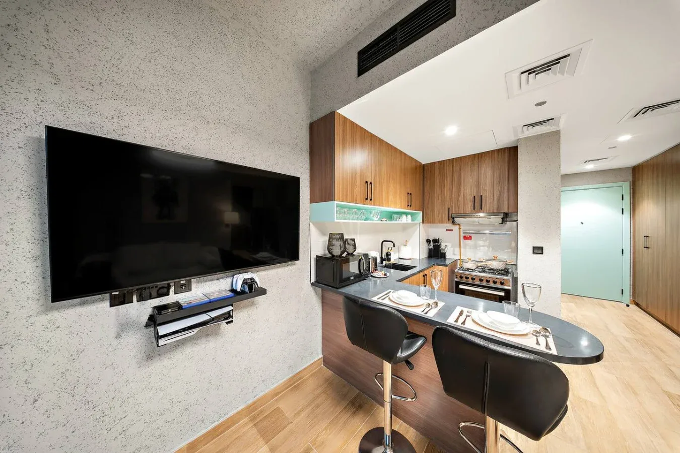 Una cocina moderna con una barra para desayunar y un televisor grande montado en la pared.