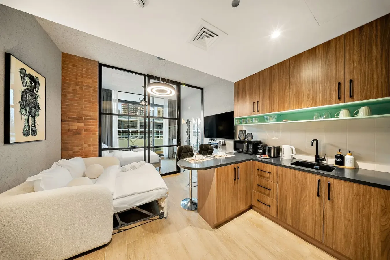 Una sala de estar y cocina de concepto abierto, con gabinetes de madera y un sofá seccional blanco.