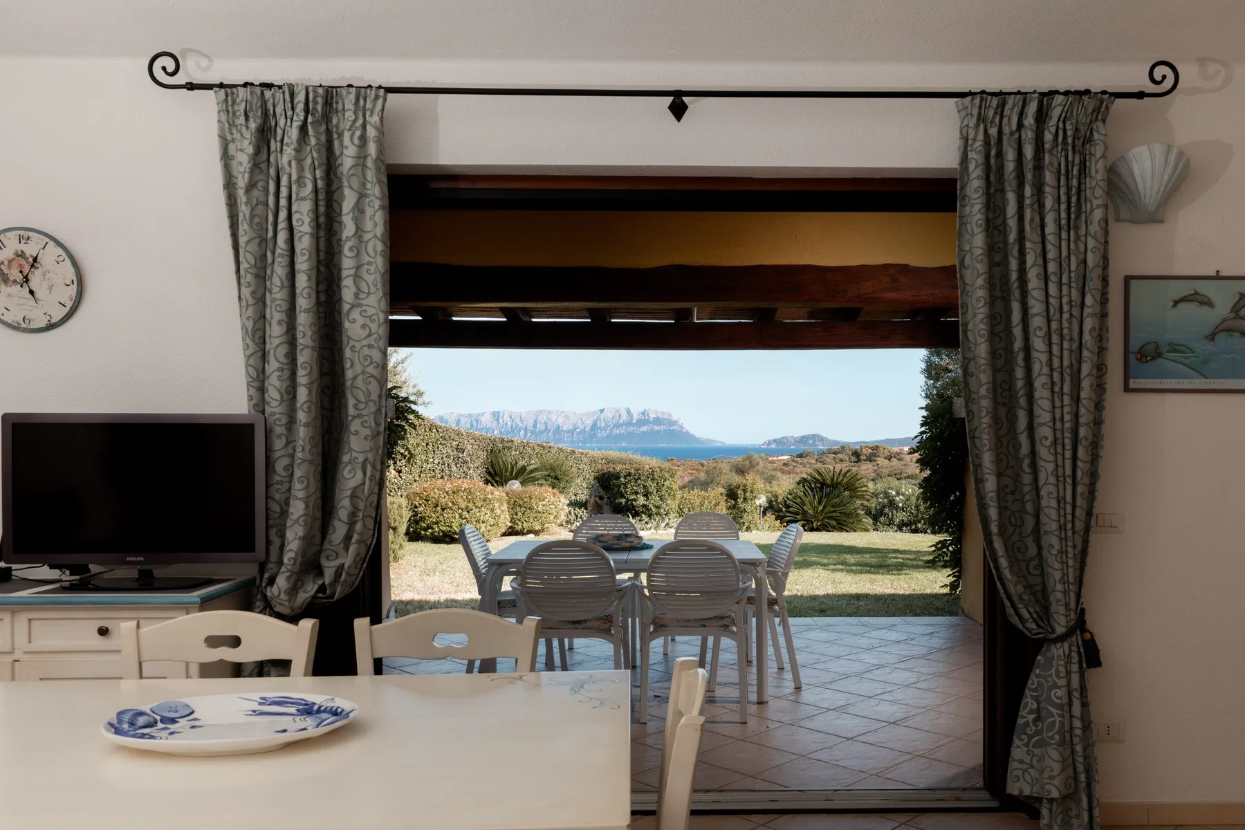 Un comedor se abre a un patio con asientos al aire libre y montañas a lo lejos.