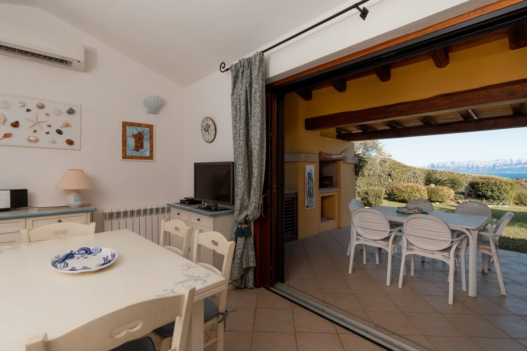 Un comedor se abre a un patio cubierto con una mesa y sillas.