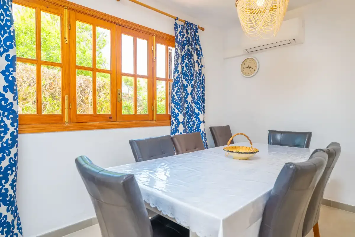 A dining room with a table and chairs beside a large window.