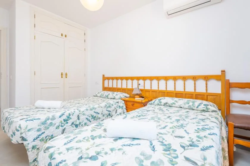 A bedroom with two beds dressed in white floral-patterned bedding.