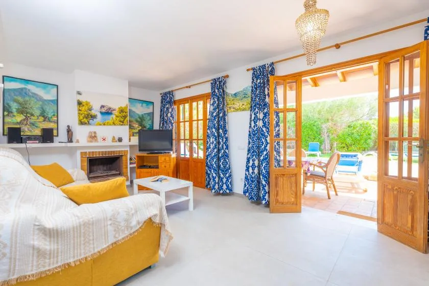 A bright living room with seating and open wooden doors overlooking a patio.