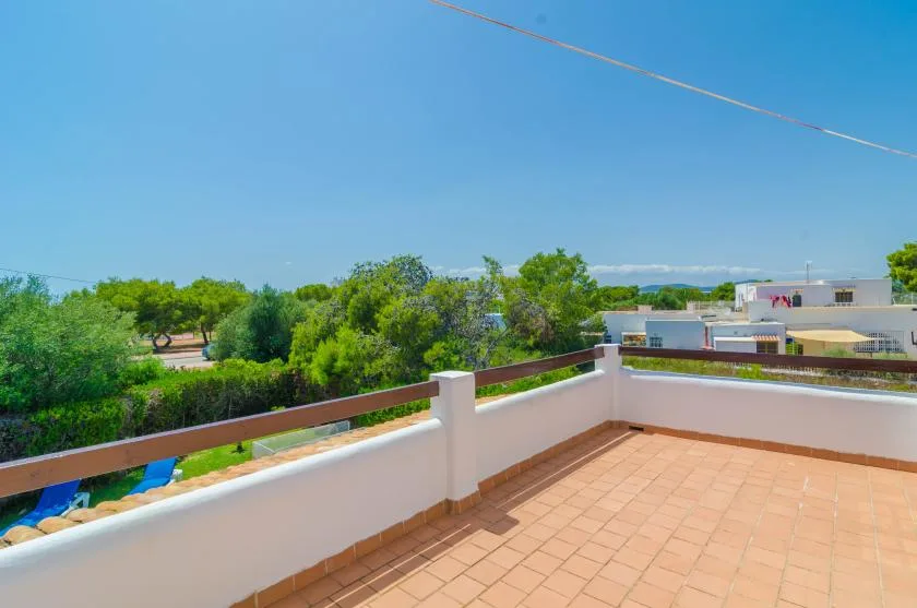 A sunny rooftop terrace overlooks green trees and nearby buildings.