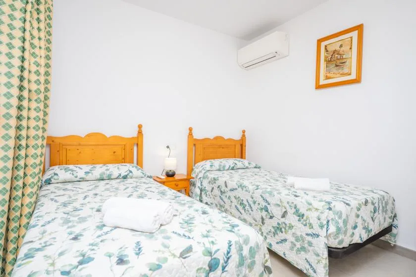 A bedroom with two beds dressed in leafy-patterned bedding.