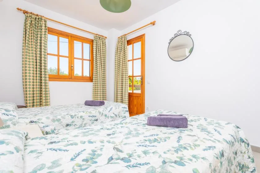 A bedroom with floral bedding, curtained windows, and a wooden door.