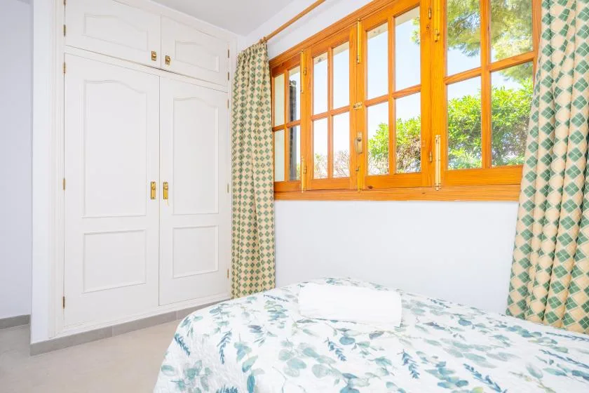 A bedroom with a patterned bed beside a row of wooden windows.