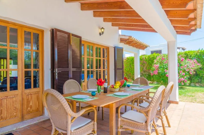A covered outdoor dining area with a wooden table and surrounding seating.