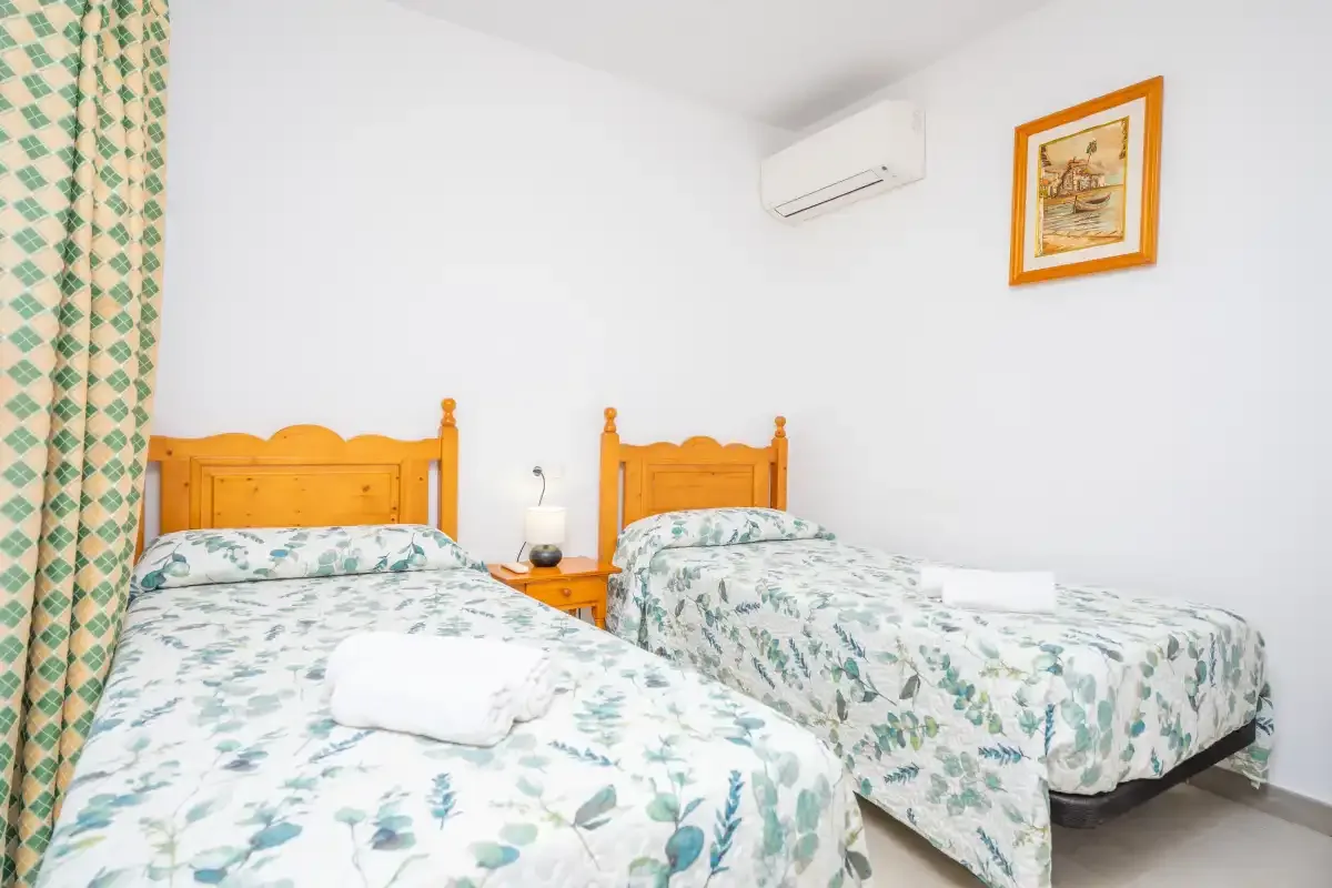 A bright bedroom with two beds dressed in floral-patterned bedding.
