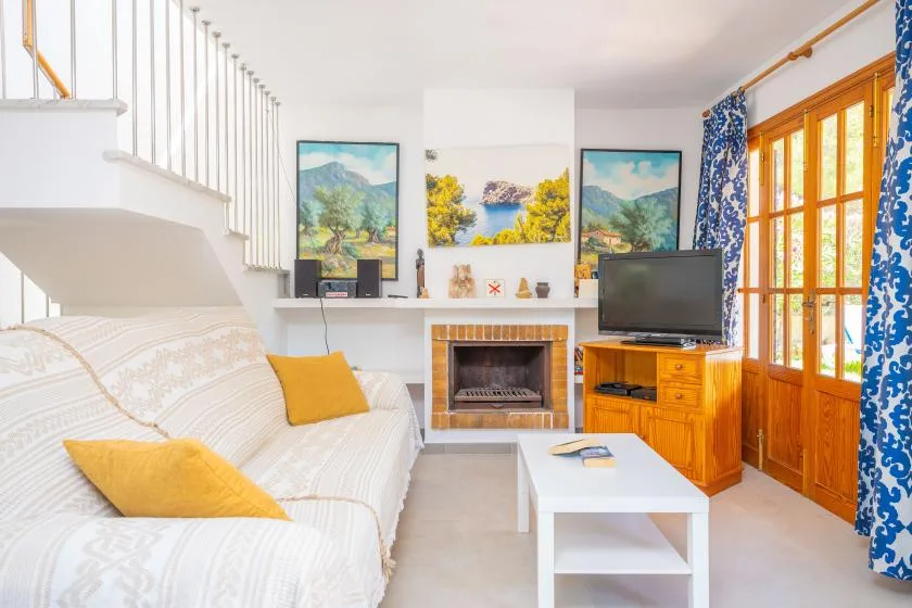 A living room with a sofa, coffee table, fireplace, and television.