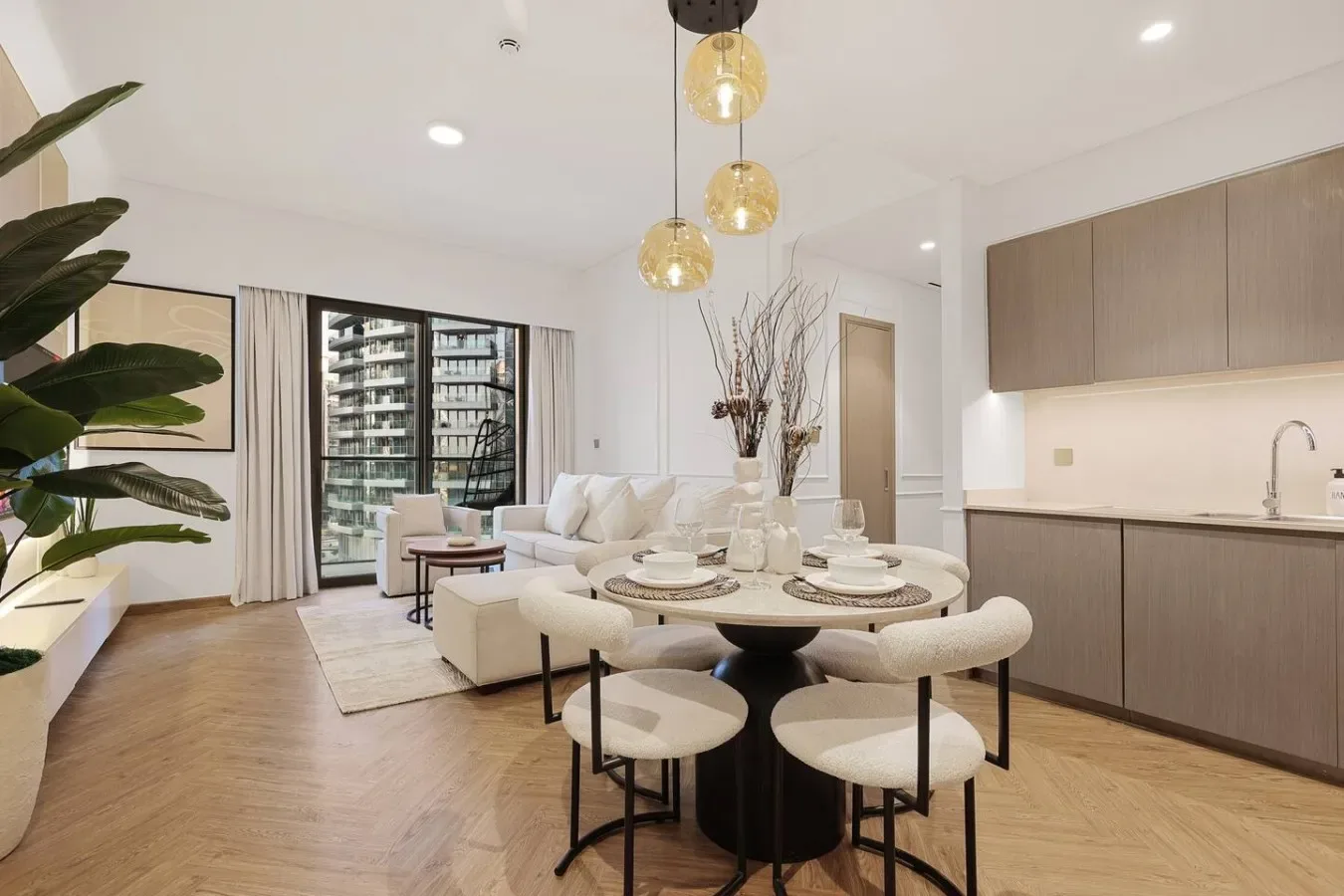 Un luminoso espacio abierto de comedor y sala de estar con mesa, asientos y grandes ventanas.