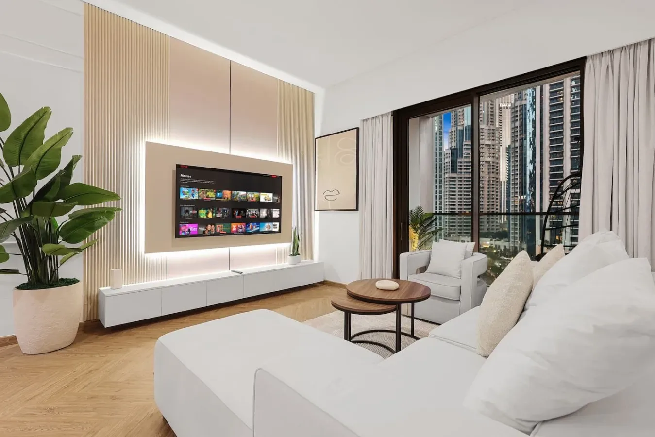 Una sala luminosa con asientos blancos y un televisor junto a grandes ventanas.