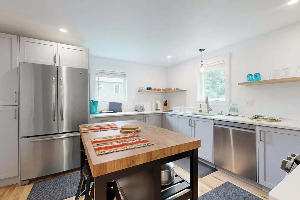 A bright kitchen with a wooden island and stainless steel appliances.