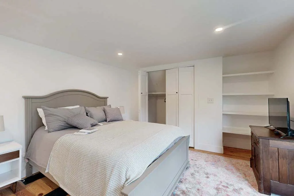 Bedroom with a bed, built-in shelving, and a television.