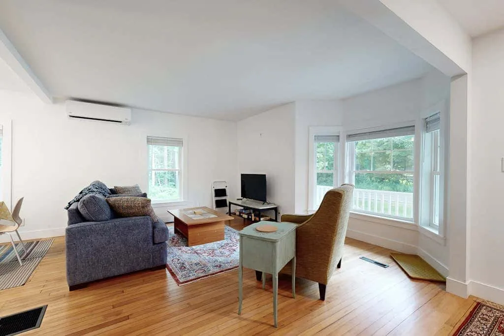 A bright living room with seating, a television, and large windows.