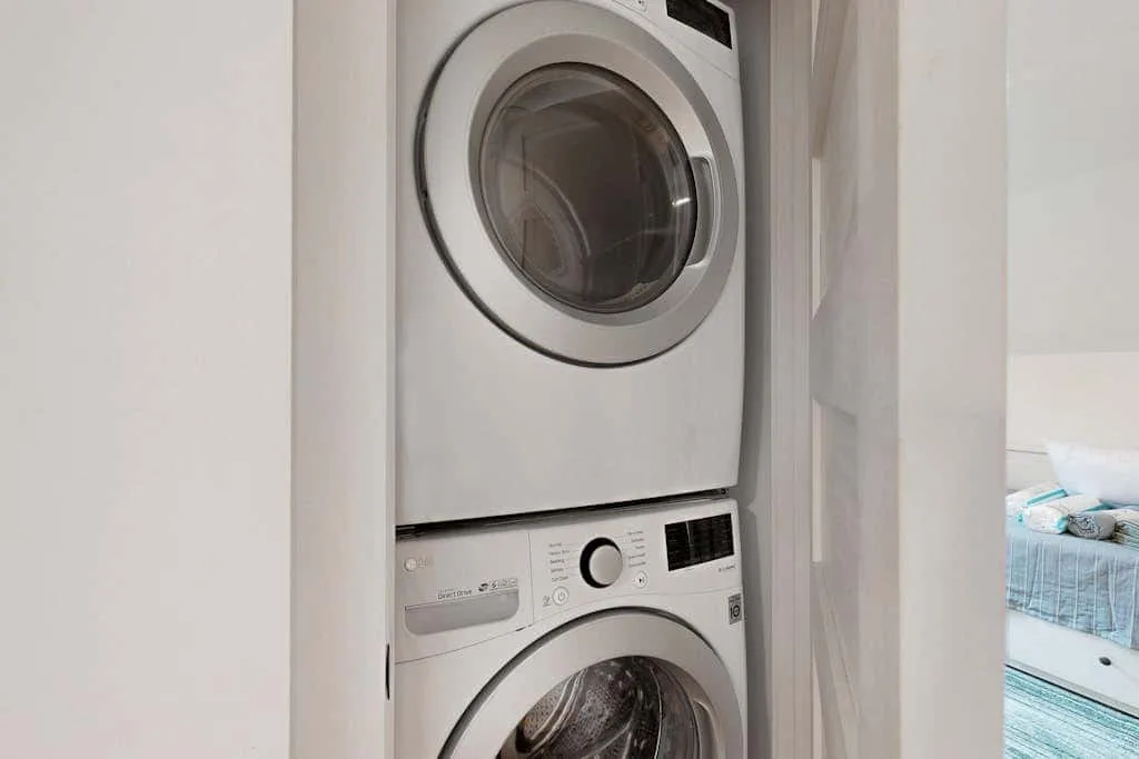 A stacked washer and dryer sit in a narrow laundry closet.