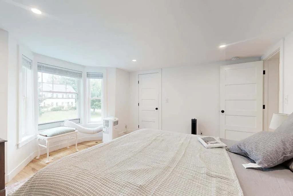 A bright bedroom with a large bed and windows overlooking the outdoors.