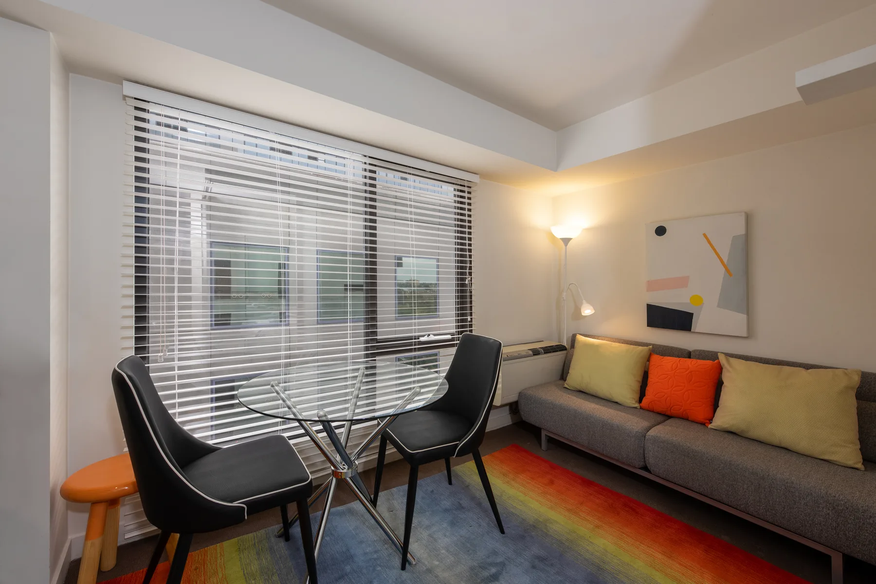 A living room with seating around a glass table beside a large window.