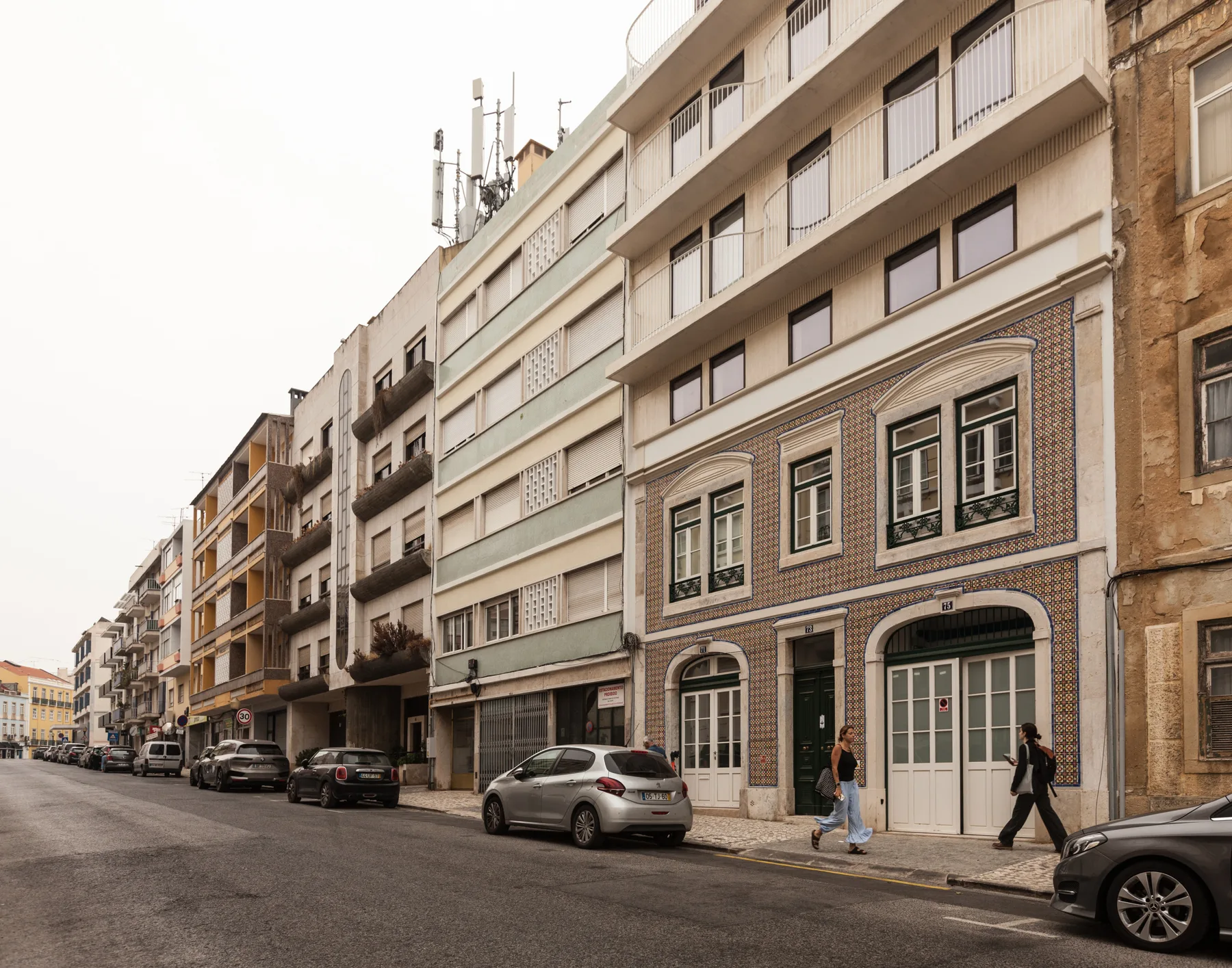 Una calle urbana flanqueada por edificios de apartamentos y coches aparcados.