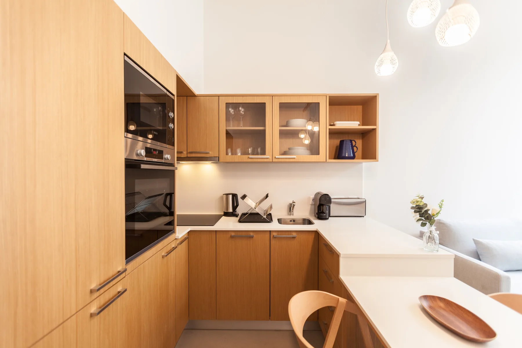 Una cocina luminosa con armarios de madera y una encimera blanca.