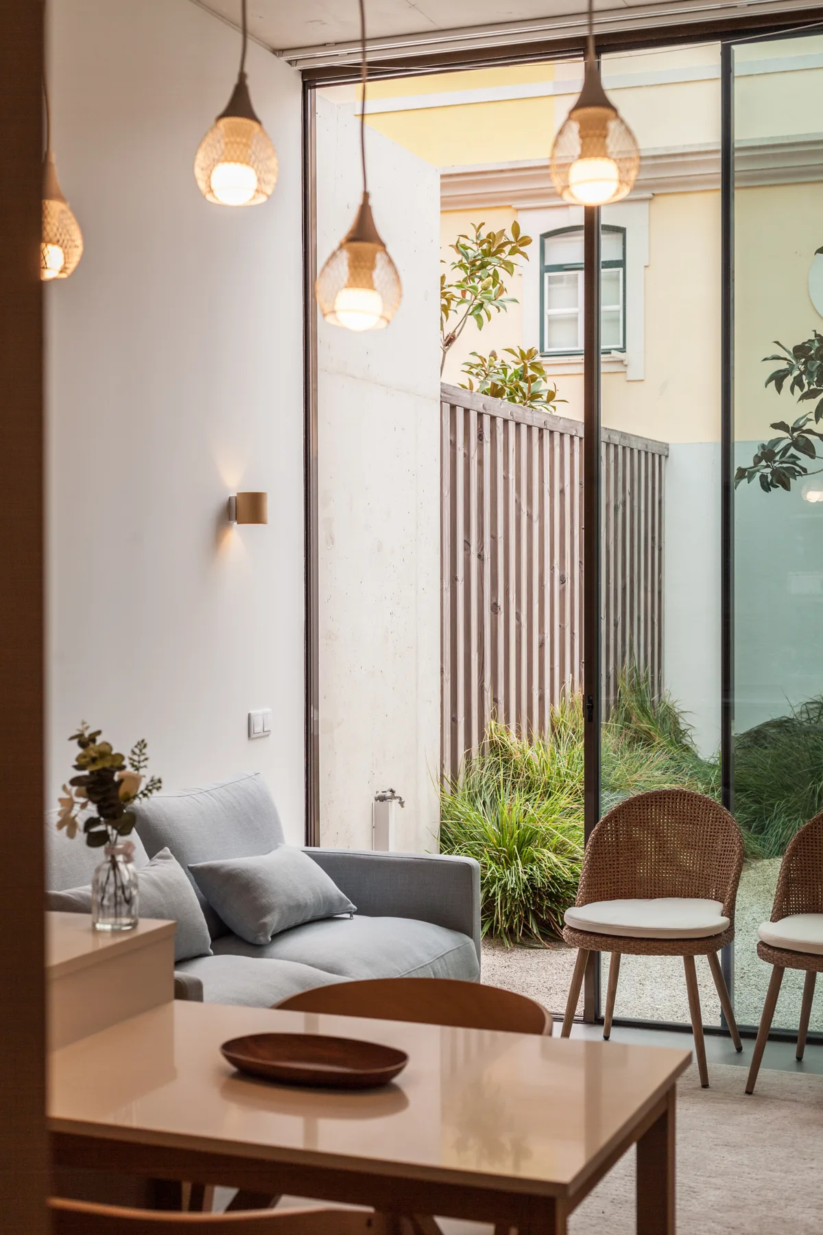 Una sala de estar con asientos y una puerta de vidrio hacia un patio con plantas.