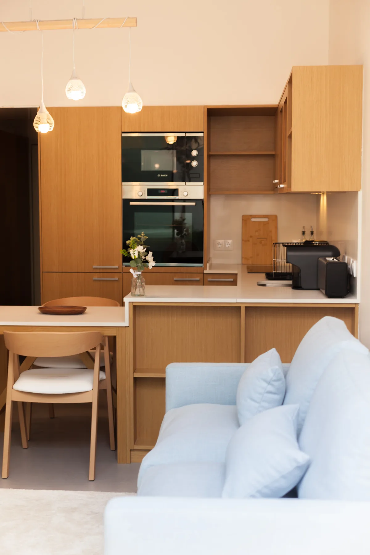 A modern kitchen and dining area with a light-colored sofa in the foreground.