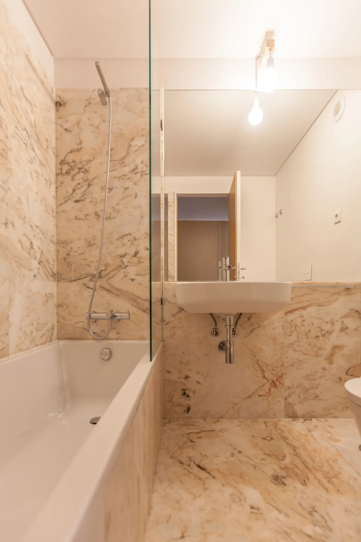 Un baño con bañera, lavabo de pared y espejo grande.