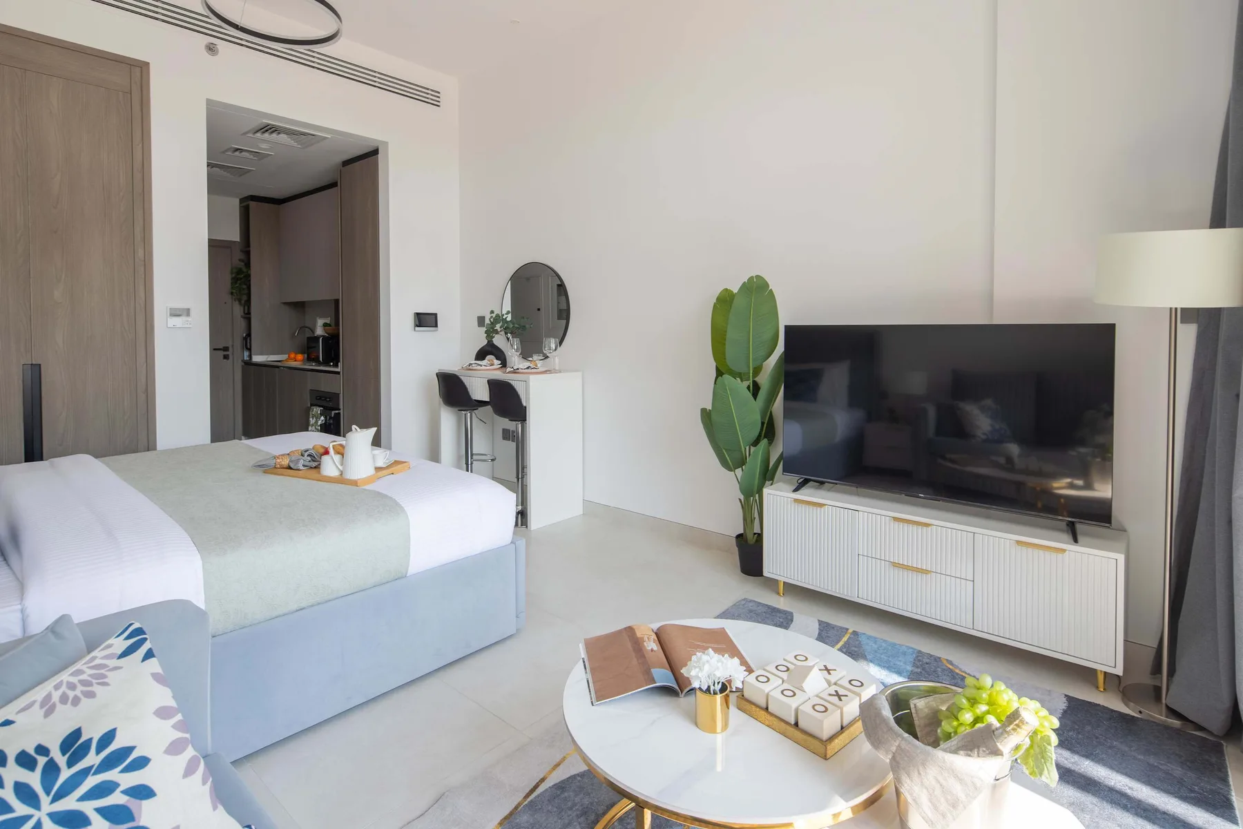 Un dormitorio luminoso con una cama, un televisor y una pequeña zona de estar.