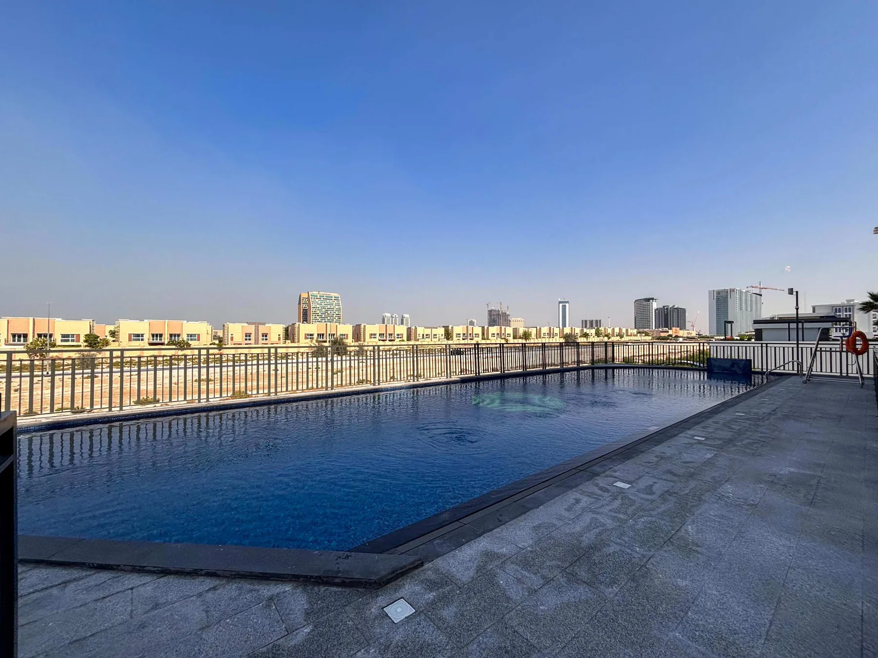 Una piscina en la azotea da a edificios bajos y un horizonte urbano distante.