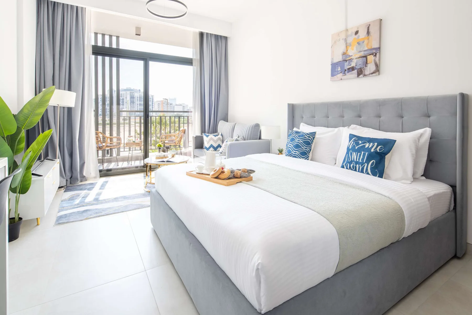 Un dormitorio luminoso con una cama grande junto a puertas corredizas de vidrio y un balcón.