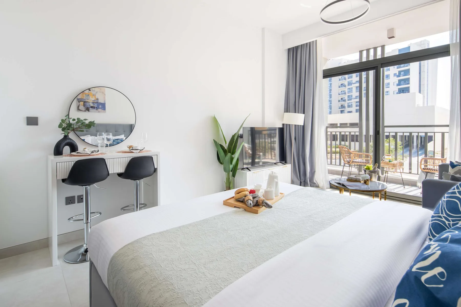 Un dormitorio luminoso con una cama grande y puertas corredizas de vidrio hacia un balcón.